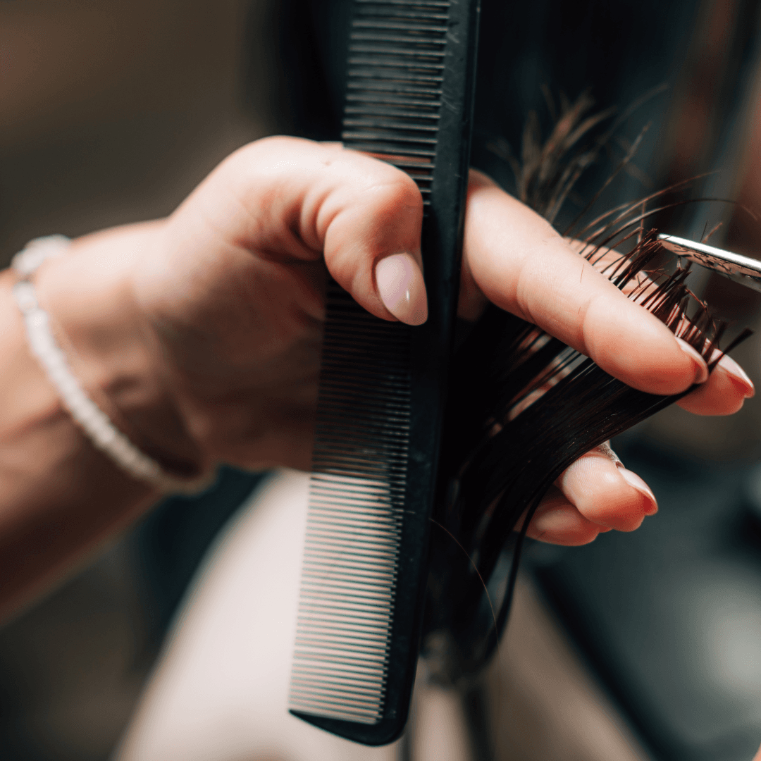 Close-up of a professional stylist cutting hair with scissors and comb – representing expert hair cutting and styling services at The Pamper Suite in Bexley.