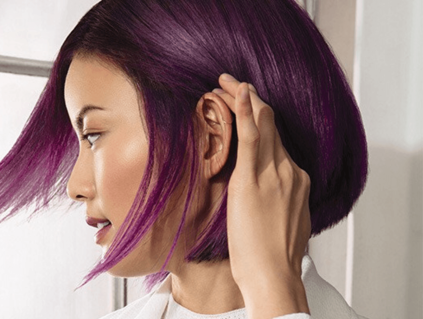 Side profile of a woman with sleek, rich purple hair running her fingers through a bob — representing a vibrant root colour top-up at The Pamper Suite in Bexley.